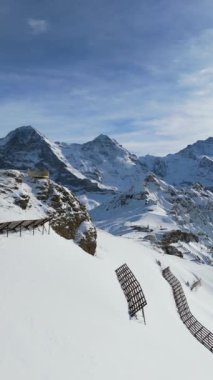 Eiger Kuzey Surat, Monch ve Jungfrau Dağları kışın. İsviçre Alpleri. İsviçre. Hava görüntüsü. Mannlichen Tepesi 'ne doğru ilerliyoruz. Şutu göster. Çığ Karşıtı Yapılar. Dikey Video