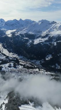 Lauterbrunnen Vadisi ve kışın Karlı Dağlar. İsviçre Alpleri. İsviçre. Hava görüntüsü. Bulutlar üzerinde ilerliyoruz. Mannlichen Top 'tan görüntü. Dikey Video