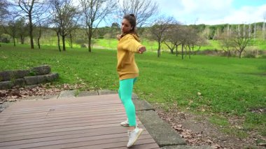 Sarı Kapüşonlu Genç Kadın Yeşil Park 'ta Zumba Dansçısı. Fitness Dansı. Tam Vuruş