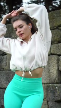 Beyaz ceketli, dans eden, dışarıda dans eden genç ve güzel bir kadın. Kovboy Vuruşu. Dikey Video