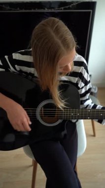 13 yaşında, evde gitar çalan genç bir kız. Dikey Video.