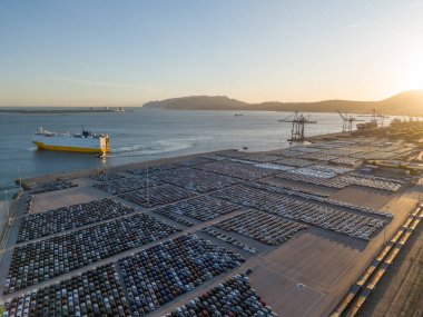 RORO Kargo Gemisi ve Yeni Arabalar Port 'ta Sunset' te Büyük Tam Otopark 'ta Dağıtıma Hazır. Araba Deposu, Otomotiv Endüstrisi. Okyanus ve Dağlar. Setubal, Portekiz. Hava Görünümü