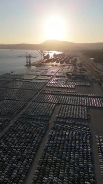 Port Ready 'deki Sunset' te Büyük Otoparktaki Yeni Arabalar Dağıtıma Hazır. Otomotiv endüstrisi. Setubal, Portekiz. Hava görüntüsü. İlerleyin, ilerleyin. Şutu göster. Dikey Video