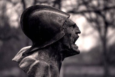 Bulanık bir arkaplan önünde yerde duran bir heykelin yakın plan çekimi.