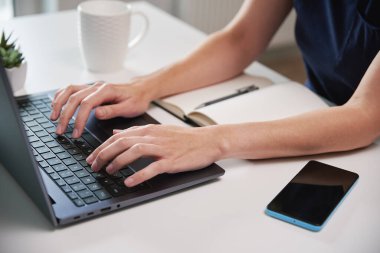 Evden çalışan bir kadın. Oturma odasında uzaktan çalışan ve dizüstü bilgisayar kullanan serbest çalışan, klavyede yazan bir kadın.