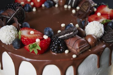 Karanlık arka planda doğum günü pastası. Koyu arkaplanda taze böğürtlen ve çikolata tatlısı ile süslenmiş pastayı kapat. Parti için lezzetli bir tatlı.