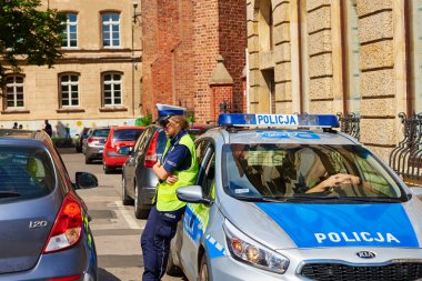 Wroclaw caddesinde bayan polis memuru. Polonya 'da polis arabasının yanında. Wroclaw, Polonya - 11 Haziran 2022