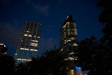 Ofis binasının ön cephesinde gece camlarında parlayan ışıklar vardı. Varşova şehri şehir merkezinde, gökdelen cepheli. Gece Şehri Panoraması. Varşova, Polonya - 4 Eylül 2022