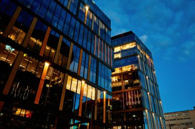 Gece vakti pencereleri aydınlatılmış ofis binası cephesi. Varşova şehri şehir merkezinde, gökdelen cepheli. Gece Şehri Panoraması