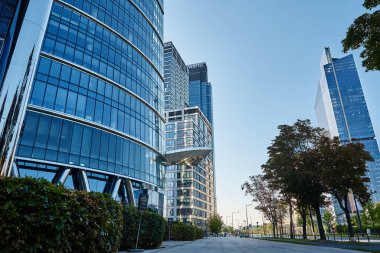 Modern şehir mimarisi, yeşil ağaçlı gökdelen cam cephe, işletme yönetim binası