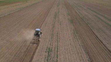 Çiftlik traktörünün üzerinde uçan dron tarlada çalışıyor, saban üstüne toz sütunları. İyi hasat için tarım arazilerinin hazırlanması. Tarım sektörü kavramı