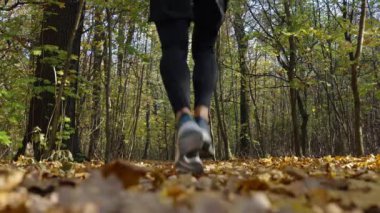 Sonbahar parkında koşan turuncu giysili bir adamın arka görüntüsü. Erkek koşucu ormanda koşuyor. Sonbahar günü açık havada aktif spor egzersizleri. Sağlıklı yaşam tarzı