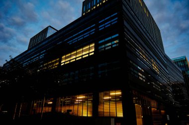 Gece vakti pencereleri aydınlatılmış ofis binası cephesi. Varşova şehri şehir merkezinde, gökdelen cepheli. Gece Şehri Panoraması