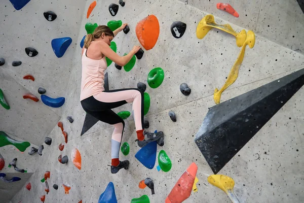 ボルダリングジムで壁に登る女性 女性登山訓練は ボルダリングクライミングの壁にかかっている アクティブライフスタイルと極端なスポーツコンセプト — ストック写真