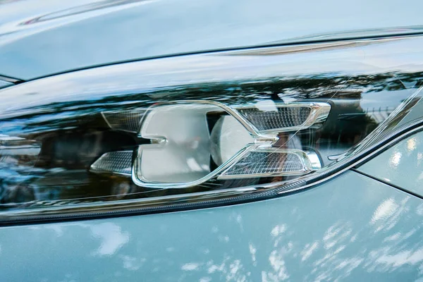 Moder car headlight with led lamp outdoors. Part of new car, turquoise color
