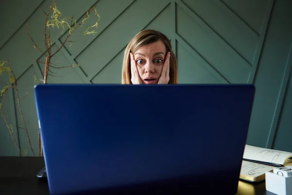 Shocked woman looking at laptop screen with rounding eyes. Excited emotional reaction at online news