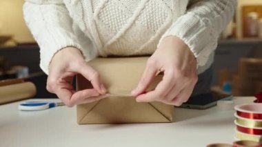 Sıcak kazaklı bir kadın, hediye paketi ve el işi kâğıdı. Kış tatili hediyesi. Noel ve Mutlu Yıllar Kutlaması