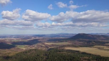 Mavi gökyüzünde bulutlar ve yerde gölgeler. Güneşli bir sonbahar gününde, yemyeşil ormanlarla kaplı güzel dağların kuş bakışı görüntüsü. Dağ sıraları ve vadileriyle doğal manzara