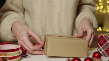 Sıcak kazaklı bir kadın, hediye paketi ve el işi kâğıdı. Kış tatili hediyesi. Noel hazırlığı ve Mutlu Yıllar Kutlaması