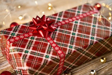 Kutlama hediye kutusunun üstünde, kurdeleli ve fiyonklu. Noel tatili için tahta arka planda Bokeh ışıkları ile hediye