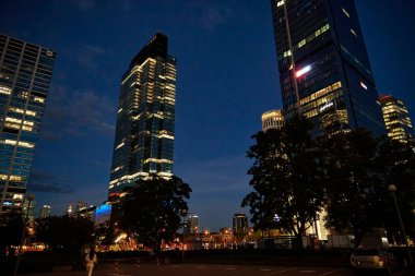 Ofis binasının ön cephesinde gece camlarında parlayan ışıklar vardı. Varşova şehri şehir merkezinde, gökdelen cepheli. Gece Şehri Panoraması. Varşova, Polonya - 4 Eylül 2022