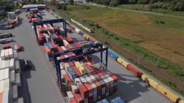 Terminaldeki MAERSK konteynırlarının yüklenmesi, demiryolu platformundaki vinçleri ve forkliftleri olan konteynırların boşaltılması, hava manzarası. Katy Wroclawskie, Polonya - 29 Eylül 2022