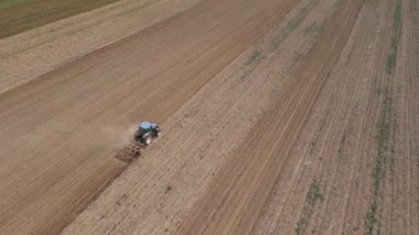 Çiftlik traktörünün üzerinde uçan dron tarlada çalışıyor, saban üstüne toz sütunları. İyi hasat için tarım arazilerinin hazırlanması. Tarım sektörü kavramı