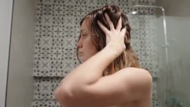 Islak saçlara saç bakım ürünü uygulayan bir kadın. Duştan sonra saç için köpük kullanan bir kadın. Kadın sabah hijyenik rutini