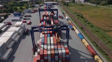Terminaldeki MAERSK konteynırlarının yüklenmesi, demiryolu platformundaki vinçleri ve forkliftleri olan konteynırların boşaltılması, hava manzarası. Katy Wroclawskie, Polonya - 29 Eylül 2022