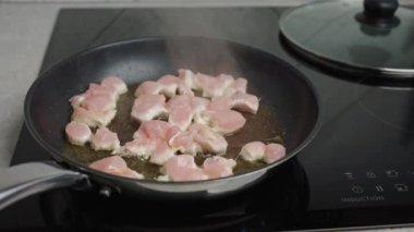 Pieces of cheacken cooking in frying pan, close up