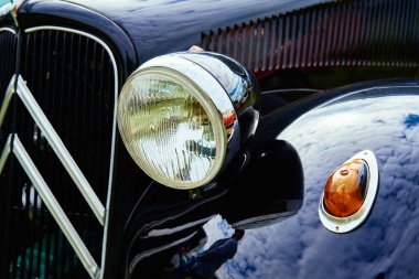 Classic car details. Headlight of black retro car. Katy Wroclawskie, Poland - May 28, 2022
