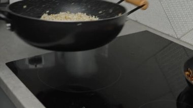 Process of cooking risotto with mushrooms. Cook mixes arborio rice in frying pan, close up. Italian cuisine dish