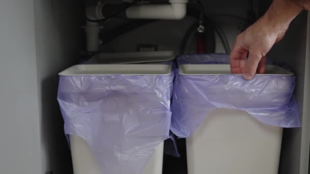 人は台所キャビネットのゴミ箱に異なった種類のゴミを投げる 廃棄物を分離するための異なるゴミ — ストック動画