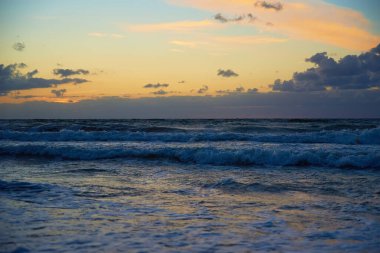 Gün batımına karşı panoramik deniz manzarası. Baltık deniz kıyılarında dalgalar ve güzel bulutlu gökyüzü