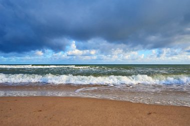 Yaz günü dalgalı deniz kıyısı. Güzel bulutlu gökyüzüne karşı Baltık sahili. Panoramik doğa manzarası