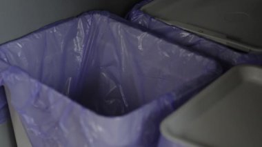 Man throws garbage into a trash can in kitcnen cabinet. Different trashes can for separating waste