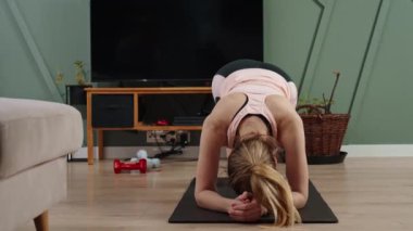 Woman doing sport exercises at home, wearing fitness watch on hand. Sport training and fitness concept. Healthy lifestyle for wellness