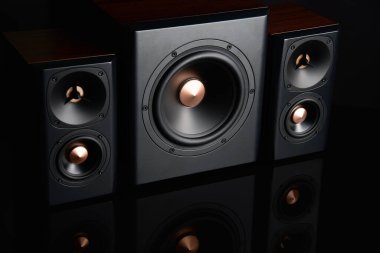 Two sound speakers and subwoofer on dark background. Set for listening music. Audio equipment