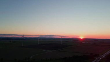 Yel değirmeni türbin jeneratörünün temiz, yenilenebilir, sürdürülebilir alternatif enerji kavramı kırsal alanda güzel günbatımı gökyüzüne karşı havadan görüntüsü