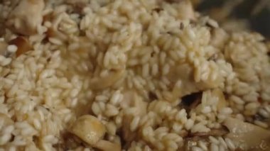 Process of cooking risotto with mushrooms. Arborio rice boiled in frying pan in home kitchen, close up. Italian cuisine dish