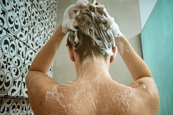 stock image Back view of naked woman taking shower in shower stall. Woman washing her hairs in bathroom. Morning hygiene