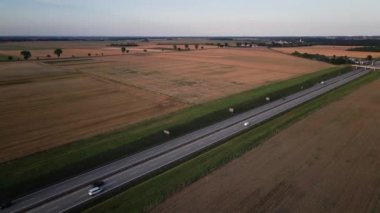 Gün batımında tarımsal tarlaları ve hava manzarası olan kırsal kesimde otoyol trafiği