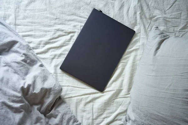 早上在未铺好的床上打开笔记本电脑 有枕头和皱巴巴的床单 自由职业者舒适的工作场所 在家工作 — 图库照片