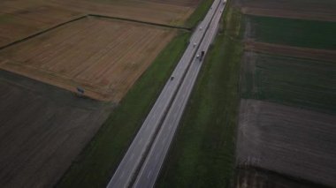Gün batımında tarımsal tarlaları ve hava manzarası olan kırsal kesimde otoyol trafiği