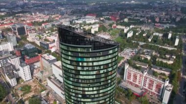 Flight over skyscraper against cityscape. High rise building facade with windows, aerial view. Sky Tower building in Wroclaw, Poland