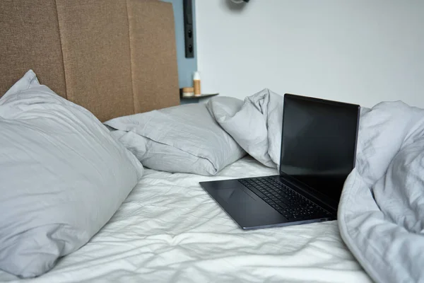 午前中に枕と砕いたベッドシートで未加工のベッドでラップトップを開いた フリーランスのための快適な職場 自宅からの仕事 — ストック写真