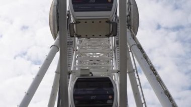 Dönme dolap mavi bulutlu gökyüzünün arka planında döner. Lunapark eğlencesi. Yaz tatili