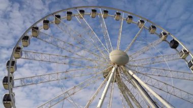 Dönme dolap mavi bulutlu gökyüzünün arka planında döner. Lunapark eğlencesi. Yaz tatili