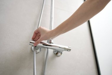 Dişi el duş musluğunu açtı. Banyo içinde modern duş seti. Hijyen kavramı