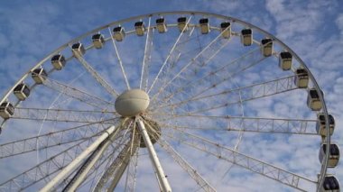 Dönme dolap mavi bulutlu gökyüzünün arka planında döner. Lunapark eğlencesi. Yaz tatili